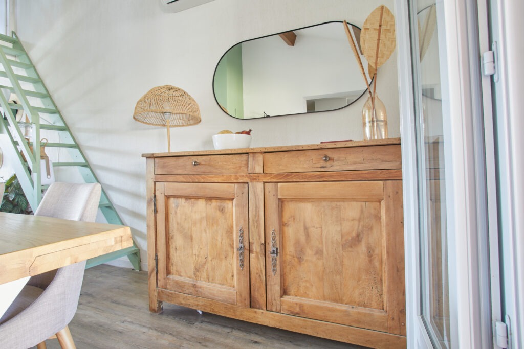 Projets architecte d'intérieur : décoration d'un loft avec buffet ancien en bois, miroir ovale et luminaire design.